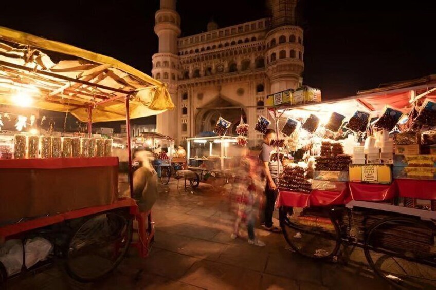 A nighttime market with food stalls and a mosque in the background. 3