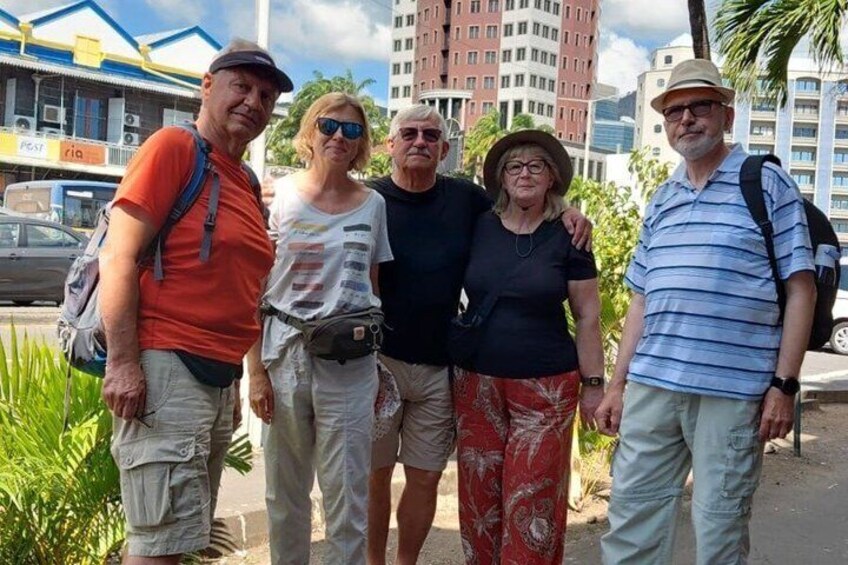 A group of people standing on a sidewalk with buildings and palm trees in the background. 3