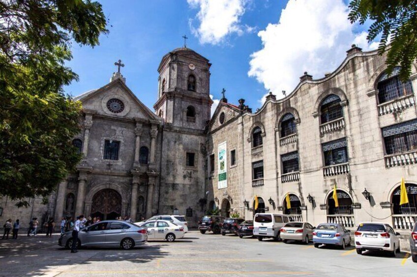 A historic church with a bell tower and multiple arches, surrounded by parked cars and people. 4