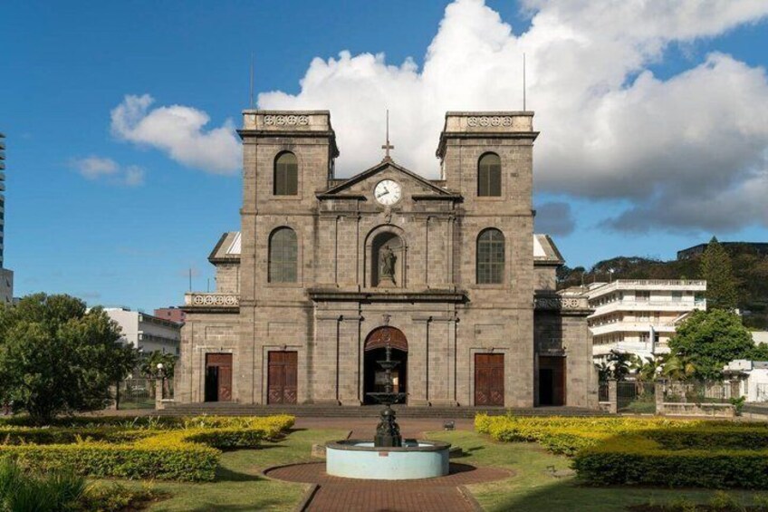 A historic church with a clock tower, surrounded by well-maintained gardens and a fountain. 4
