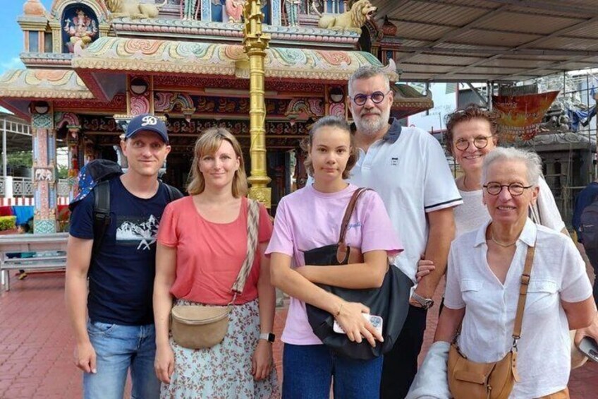 A group of people standing in front of a colorful, ornate structure with intricate designs and a golden pole. 2