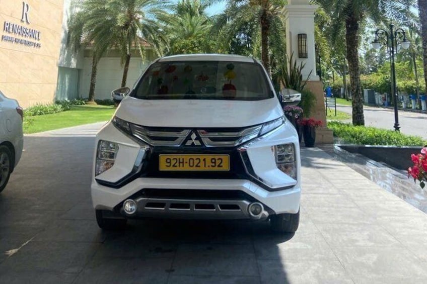 A white SUV parked in a driveway with palm trees and a building in the background. 5