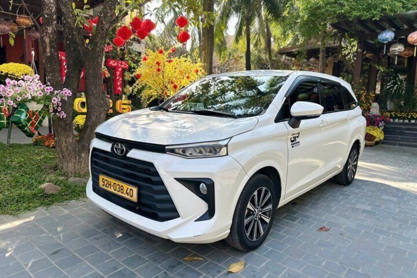 A white SUV parked on a paved area with trees and colorful decorations in the background. 4