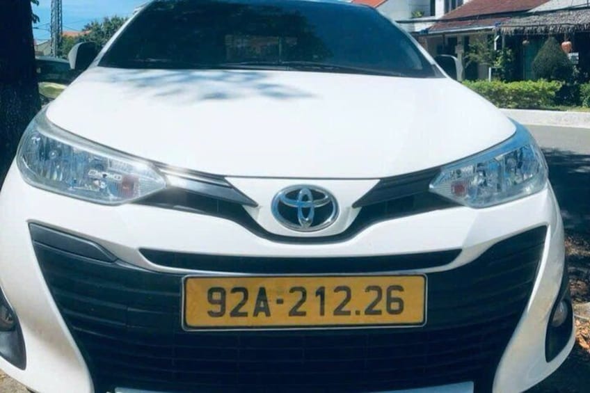 A white Toyota car with a yellow license plate. 2