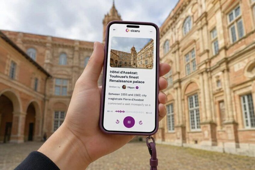 A hand holding a smartphone displaying information about the Hôtel d'Assézat, a Renaissance palace in Toulouse. 1