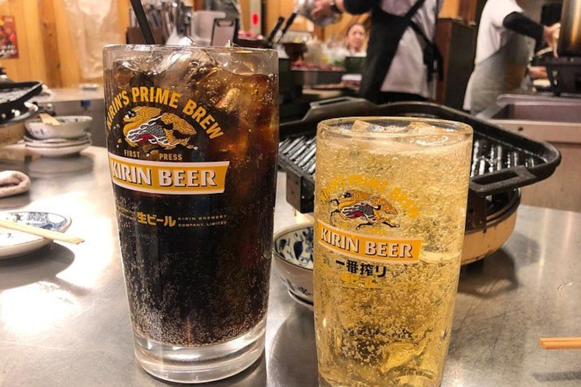 Two glasses of Kirin Beer, one dark and one light, on a counter with a grill in the background. 5