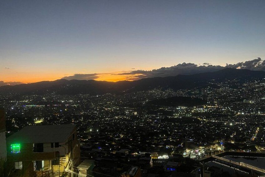 A cityscape at dusk with a mountain range in the background. 3