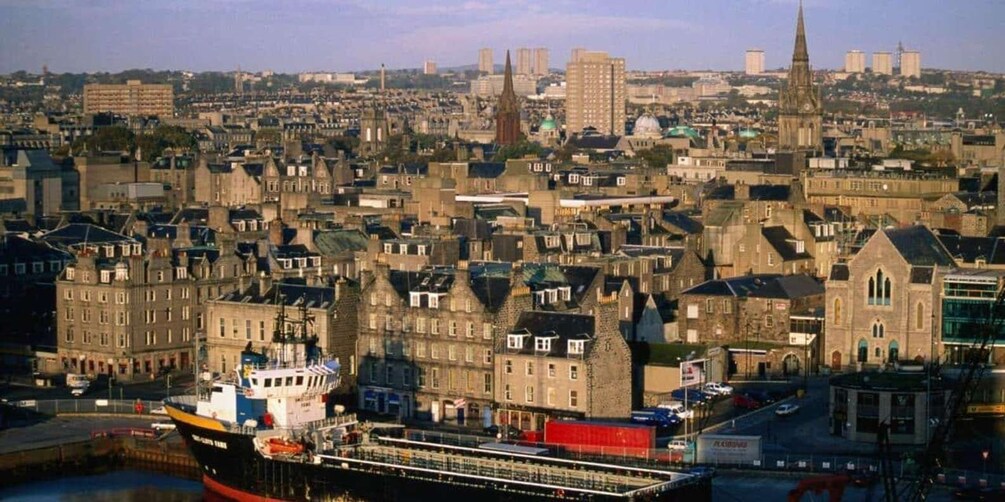 A cityscape with historic buildings, a prominent church spire, and a large ship docked at a port. 4