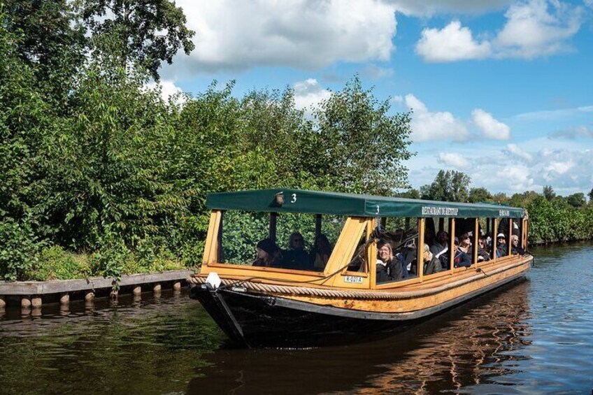 A narrowboat with passengers, surrounded by lush greenery and a calm river. 5