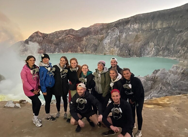 A group of people with helmets and goggles posing in front of a rocky landscape with a turquoise lake. 3