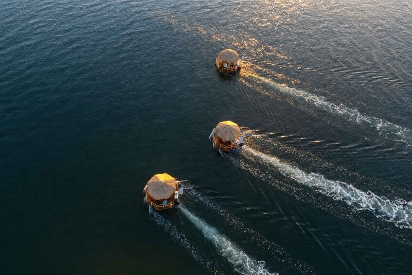 Three thatched-roof boats on the water with wake patterns. 5