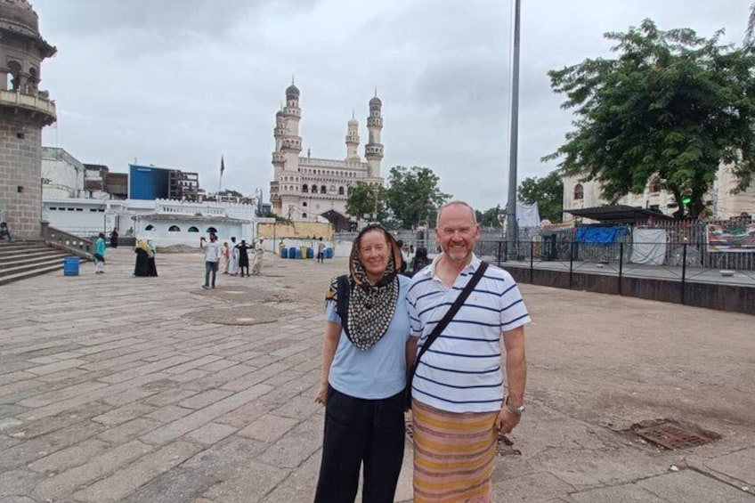 A historical building with minarets, a paved square, and a few people in the background. 3