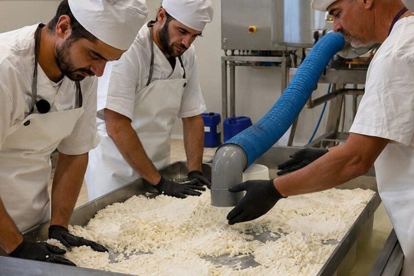 Three people in white uniforms working with a large blue hose in a food processing facility. 3
