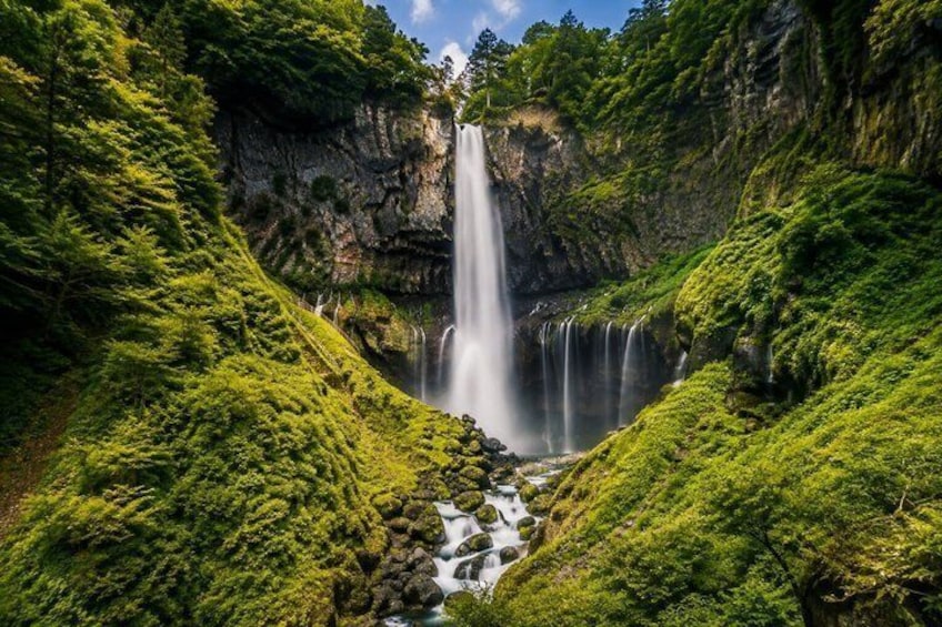 A waterfall cascading down a rocky cliff surrounded by lush green vegetation. 2