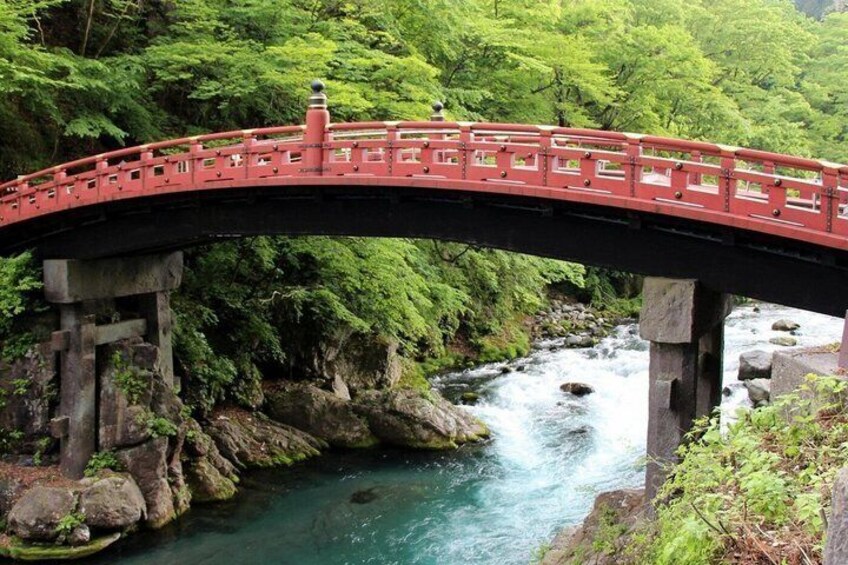 A red bridge over a river with lush greenery and rocky terrain. 5
