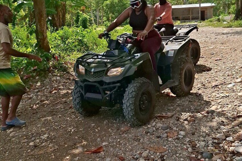 A person riding an ATV on a rocky path surrounded by greenery. 3