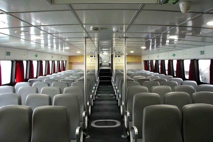 A train interior with rows of seats, a central aisle, and overhead luggage compartments. 3