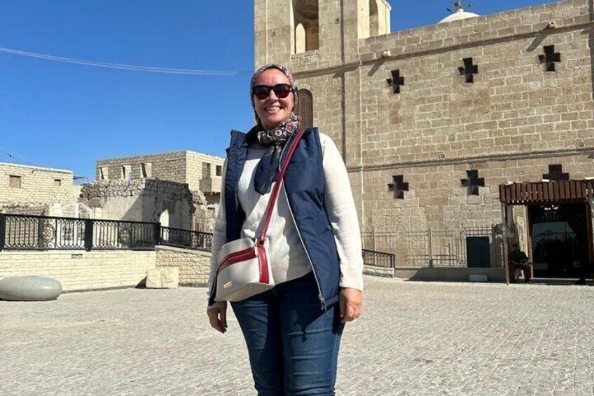 A person standing in front of a historic building with a cross on the facade. 1