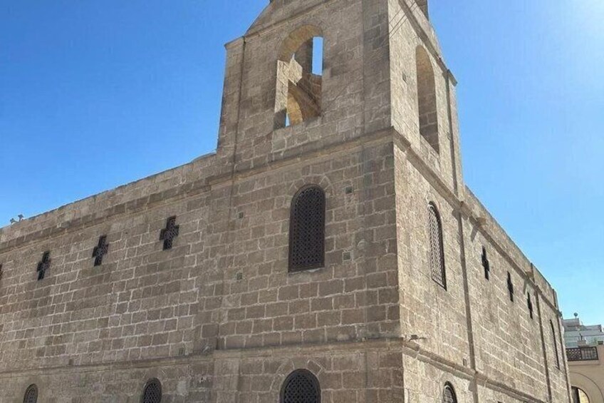 A stone church with a bell tower, arched windows, and crosses on the facade. 3