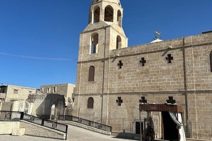 A large stone church with a bell tower, arched windows, and crosses on the facade. 5
