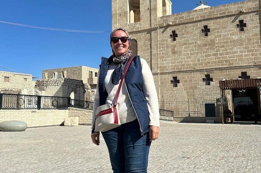 A person standing in front of a historical building with a cross on the facade. 1