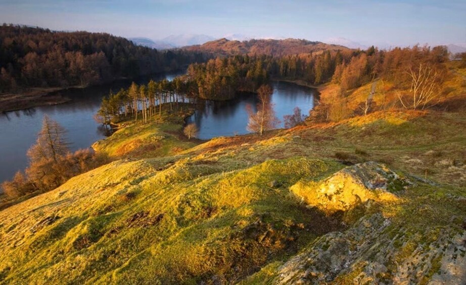 A lake surrounded by forested hills, with a clear sky above. 2