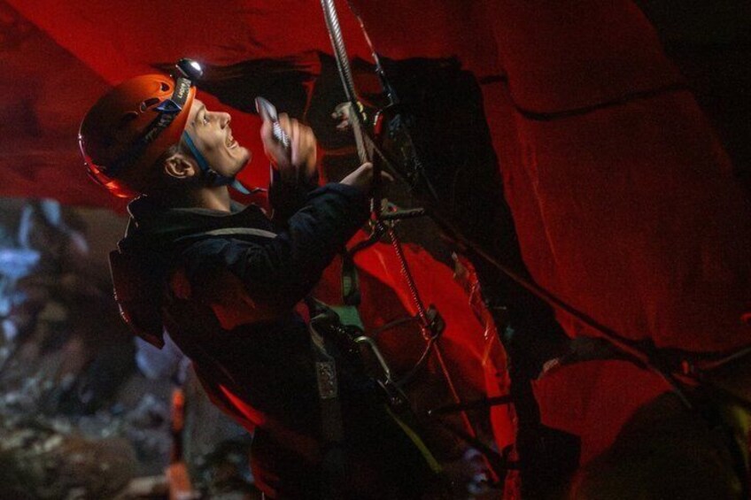 A person climbing a rope with a helmet and harness. 5