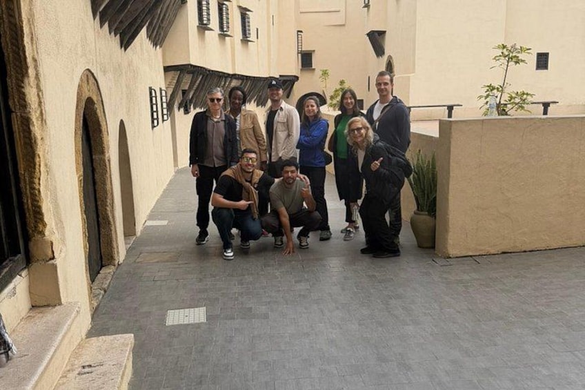 A group of people in an outdoor courtyard with arches and potted plants. 1
