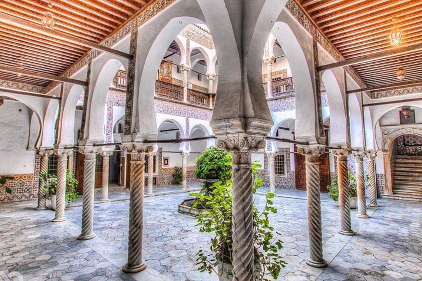 A courtyard with arches, columns, and a tiled floor. 4