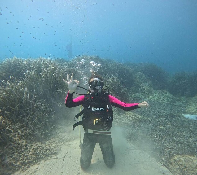 A diver underwater with a backpack labeled 'mares' and a pink long-sleeve shirt. 5