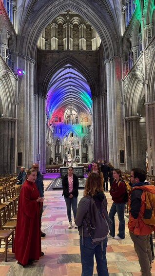 A cathedral interior with a large altar, stained glass windows, and a group of people standing in the nave. 4