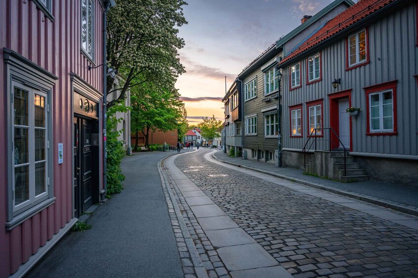 A cobblestone street lined with buildings, one with a red door and another with a red roof. 1