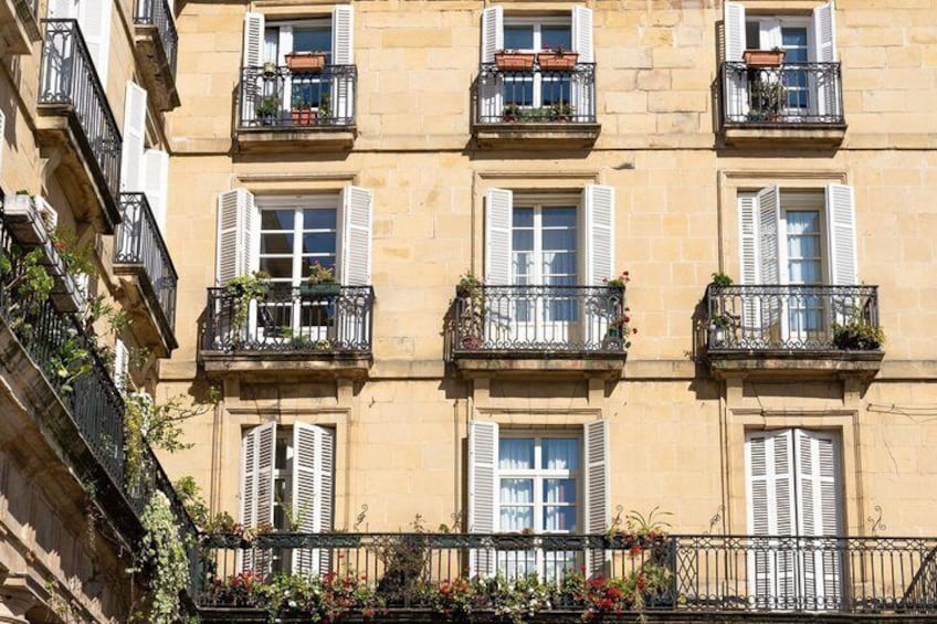 A building with multiple balconies, each with plants and flowers. 4