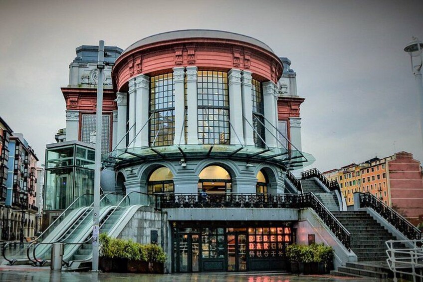 A historic building with a circular central section, large windows, and a staircase leading to the entrance. 5