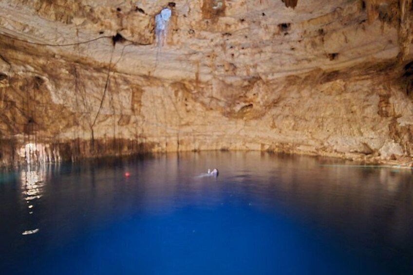 A cave with a pool of water and a person standing on a ledge. 3