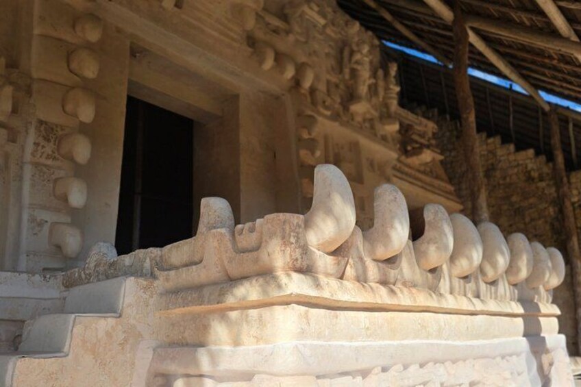A stone structure with a series of carved figures and a doorway. 4