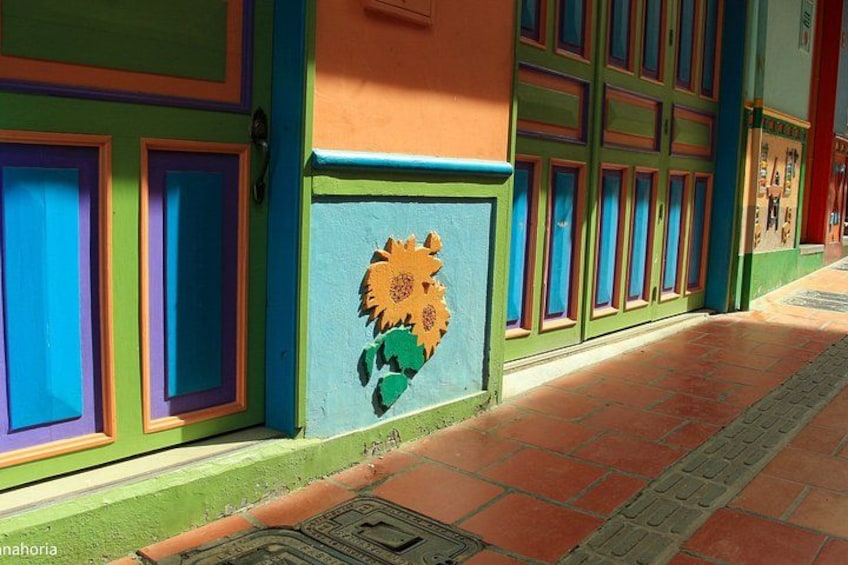 A colorful building facade with vibrant painted doors and a sunflower mural. 3