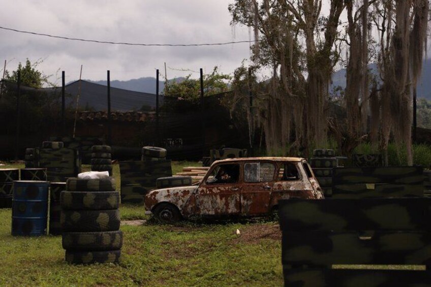 A rusty car in a rural setting with hay bales and a fence in the background. 5