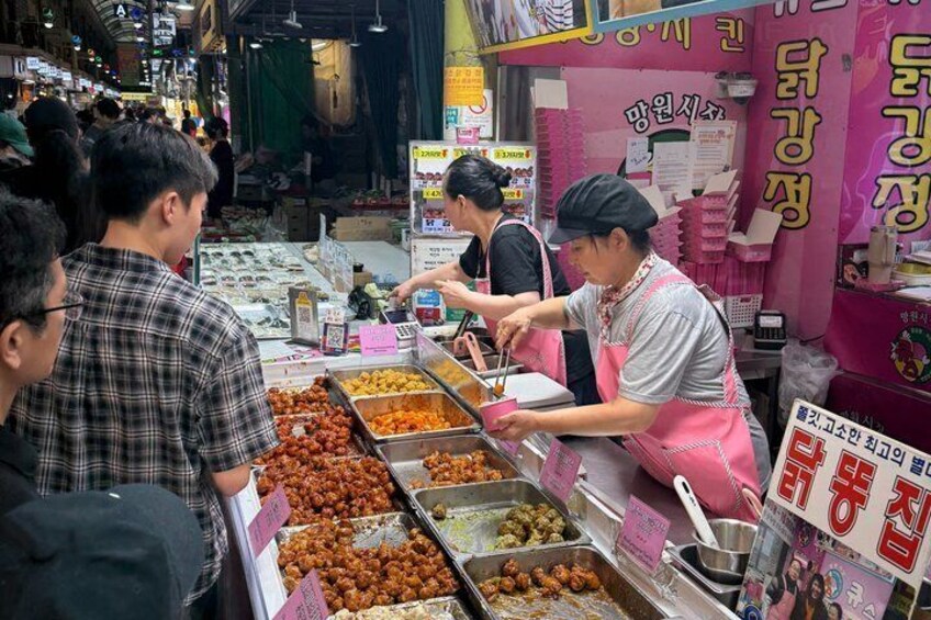 A street food vendor preparing food at a stall with various dishes displayed. 1