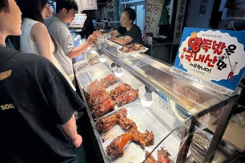 A food stall with cooked meats displayed in a glass case. 5