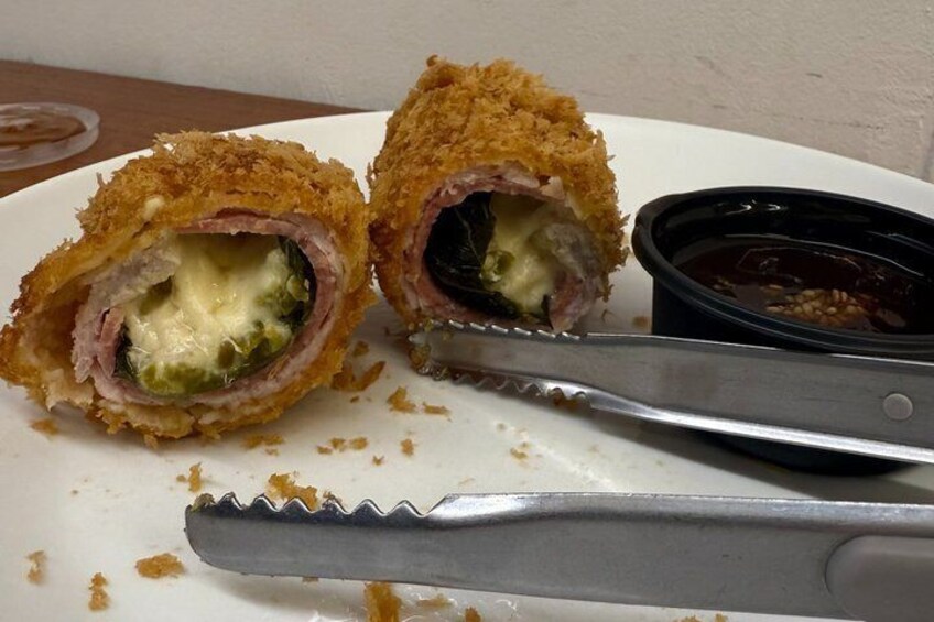 A plate with a stuffed meat dish, a knife, and a small container of sauce. 3
