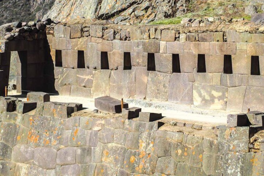 Ancient stone structures with rectangular openings and a stone bench. 2