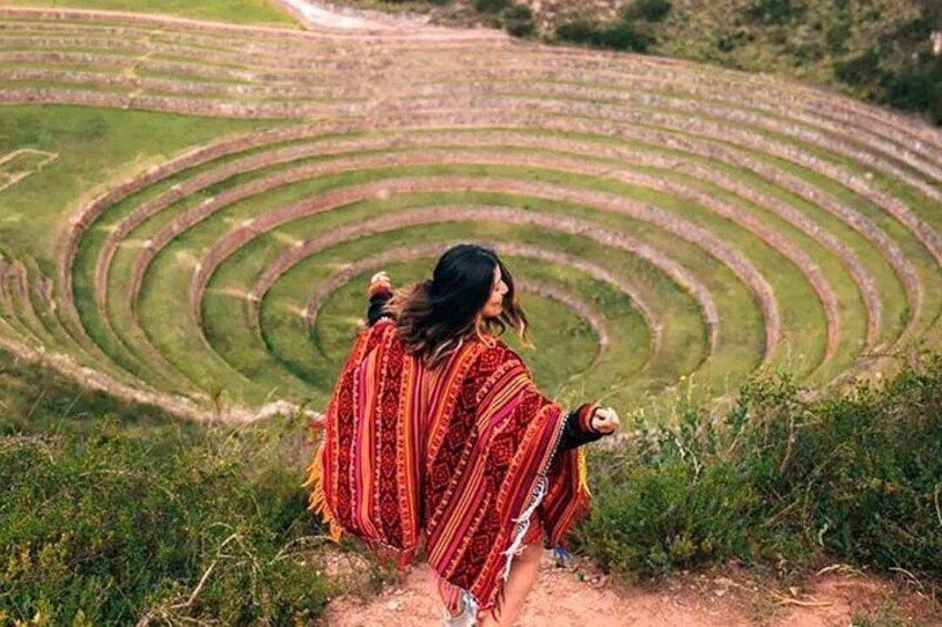 A person standing in a terraced field with a patterned blanket. 1