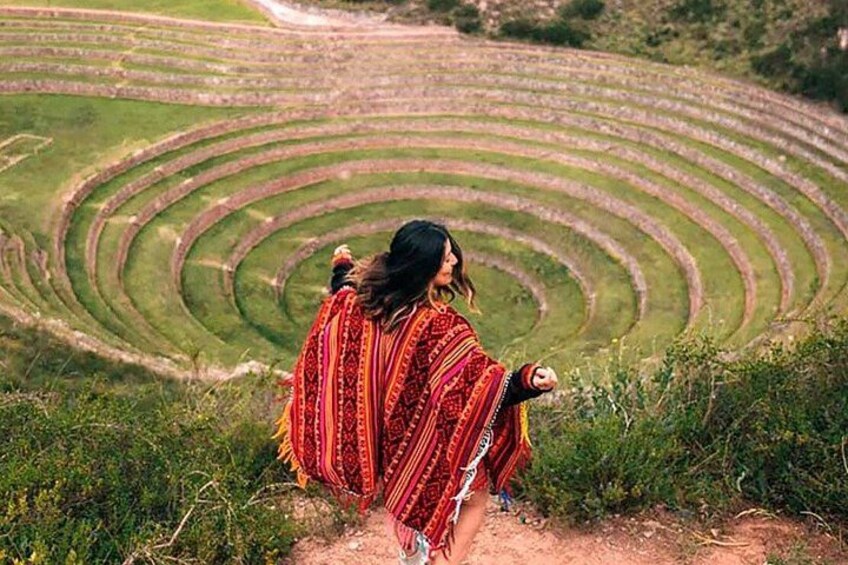A person standing on a dirt path with terraced fields in the background. 1