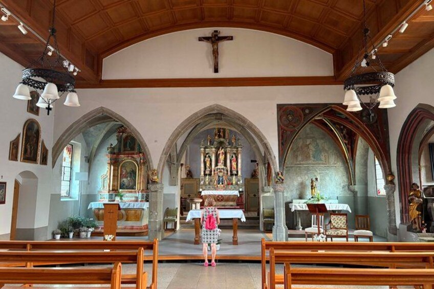 A church interior with wooden pews, a central altar, and religious statues. 2