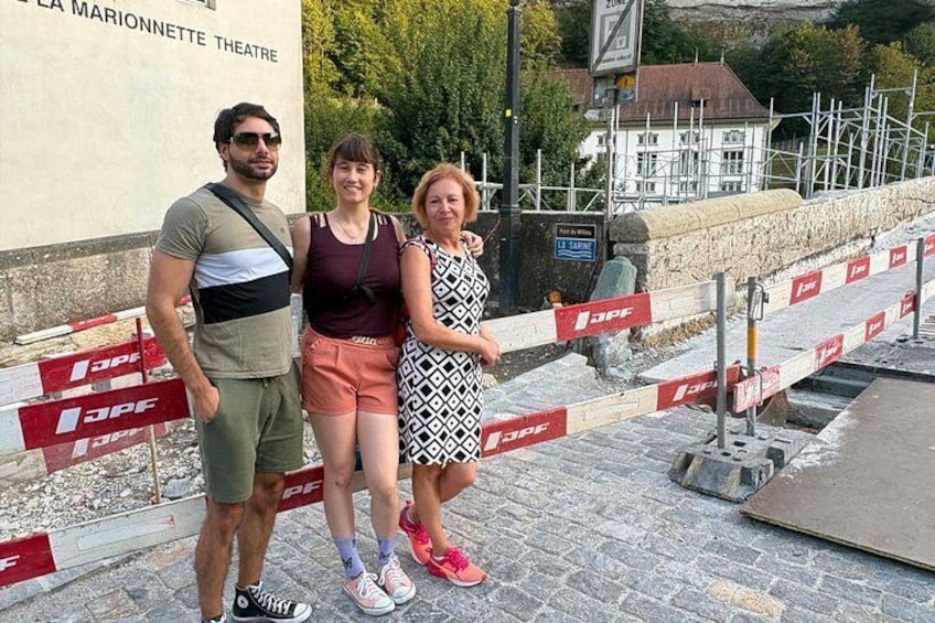 Three people standing in front of a building with a sign that reads 'LA MARIONNETTE THEATRE'. 1