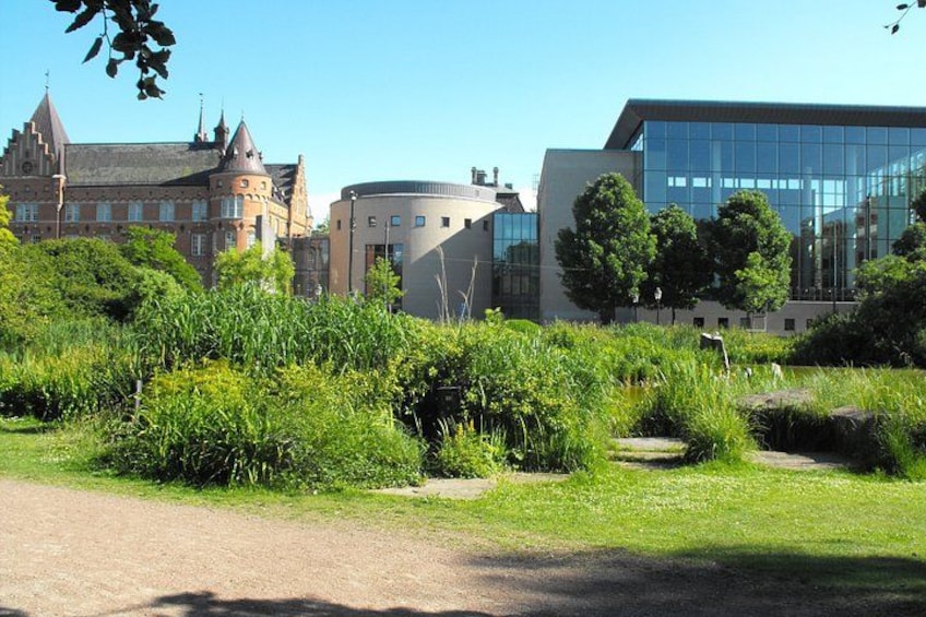 A park with a castle, modern buildings, and lush greenery. 5