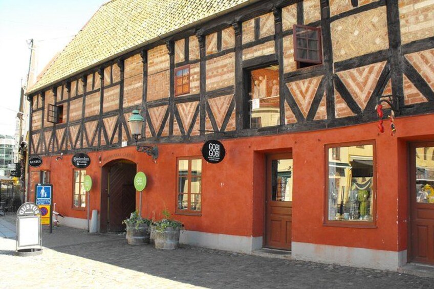 A half-timbered building with a red facade and a black timber frame. There are signs on the building, including one that says 'GAS' and another that says 'Café.' 4
