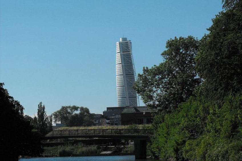 A twisting skyscraper, a bridge, and dense greenery. 3