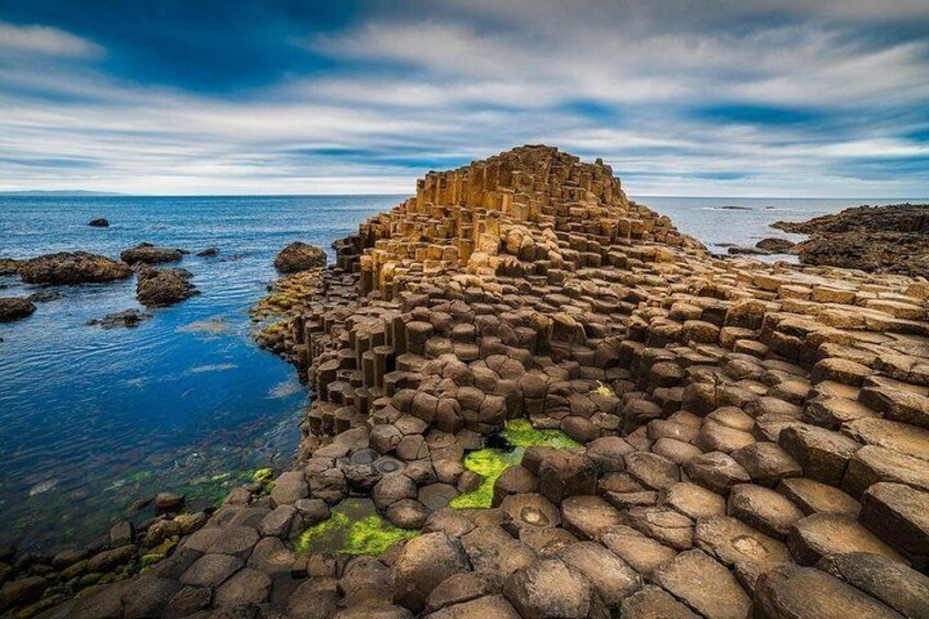 A coastal rock formation with a layered structure and a body of water. 1